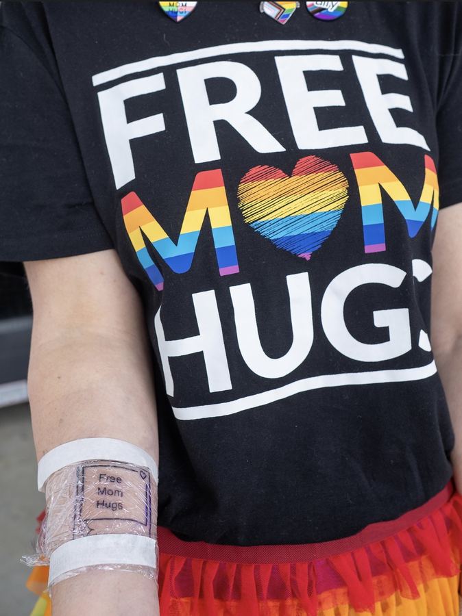 Norah wearing a Free Mom Hugs shirt, with a matching flash tattoo on her forearm.