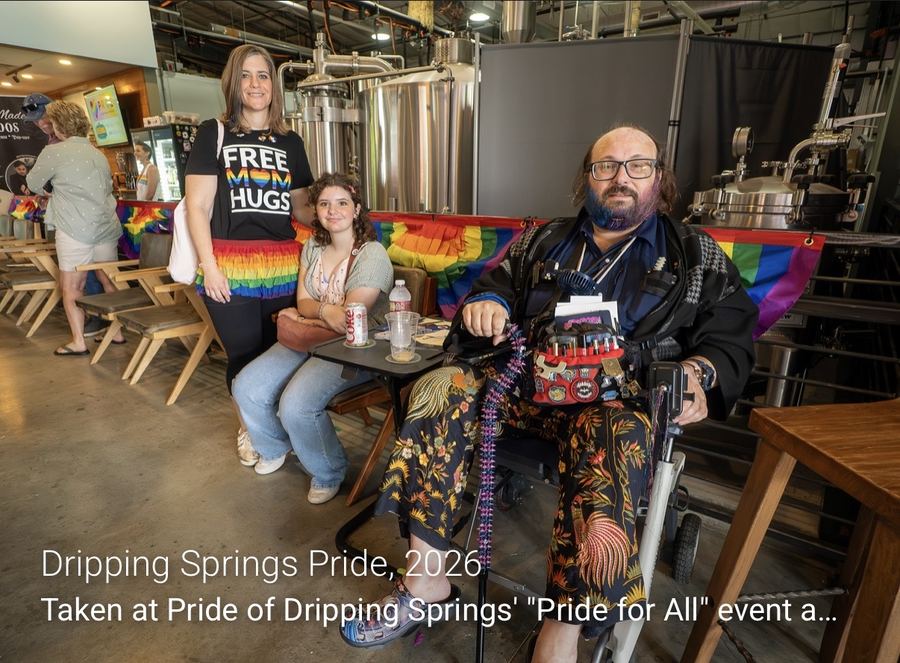 Ryan, Norah and Lacey together at Dripping Springs Pride, in front of rainbow bunting at the brewery venue.